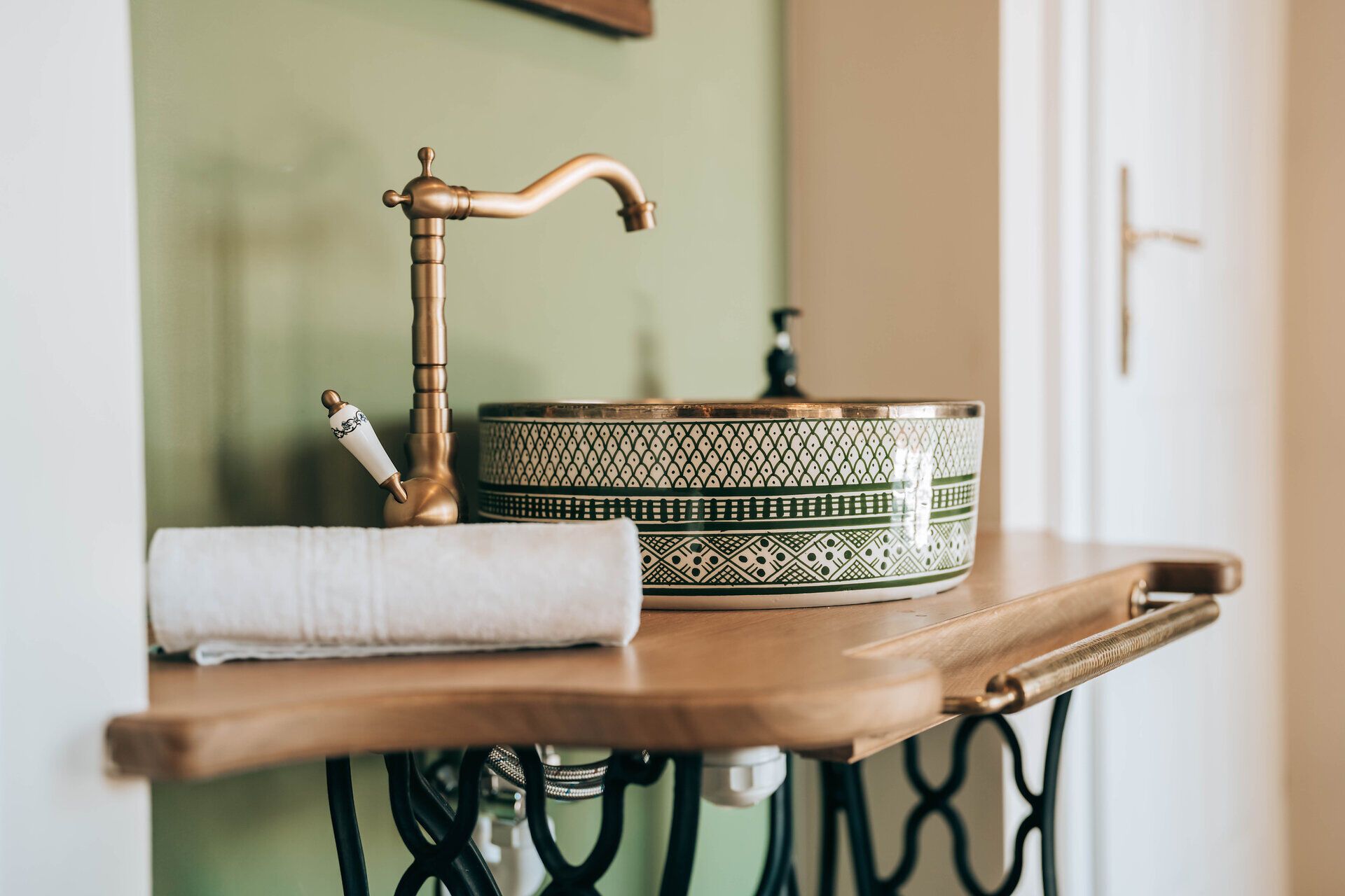 Ein stilvolles Badezimmer mit einem dekorativen Waschbecken und einem goldenen Wasserhahn auf einem Holzwaschtisch.