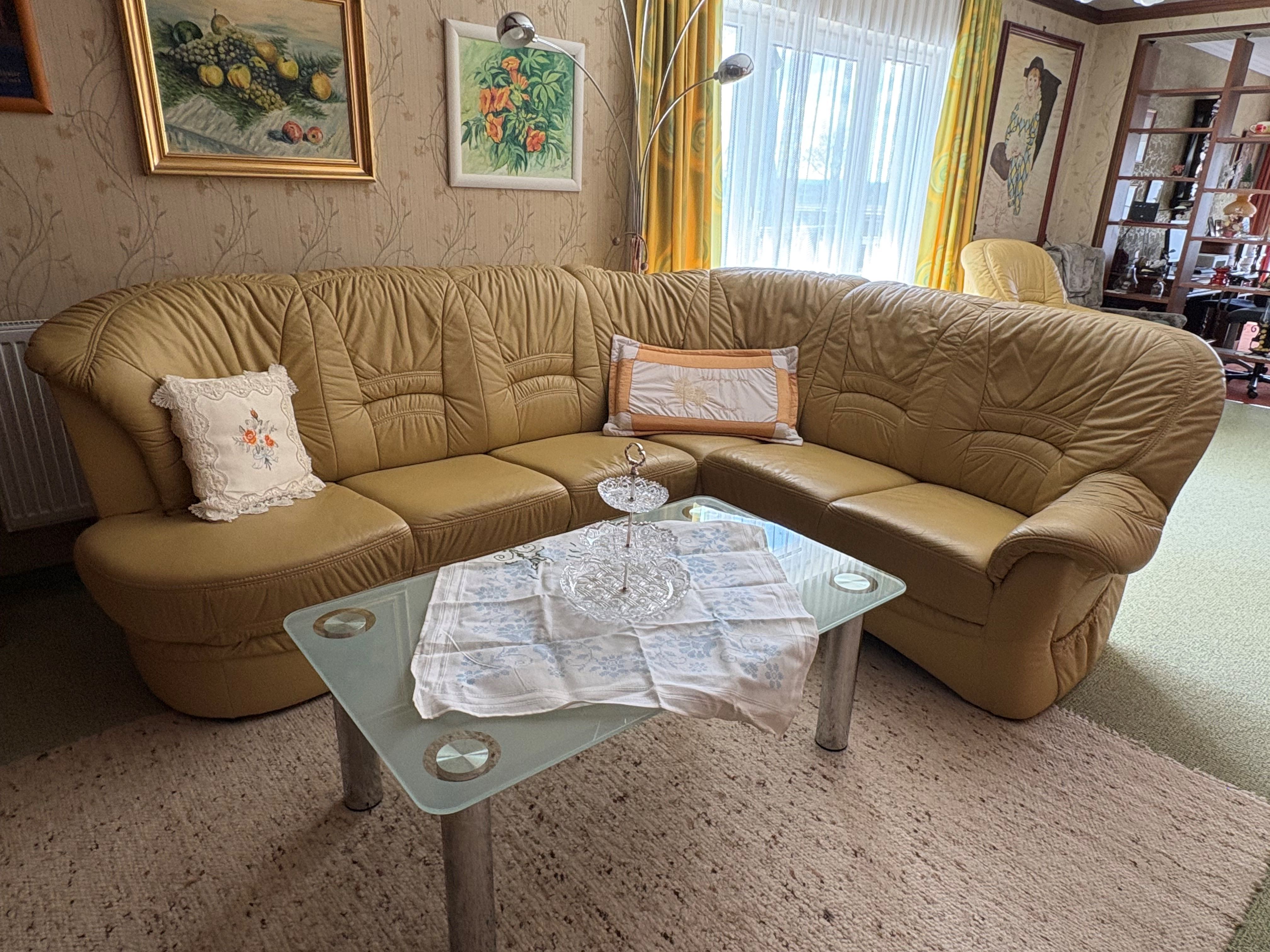 Wohnzimmer mit gelbem Ledersofa, Glastisch und dekorativen Kissen.