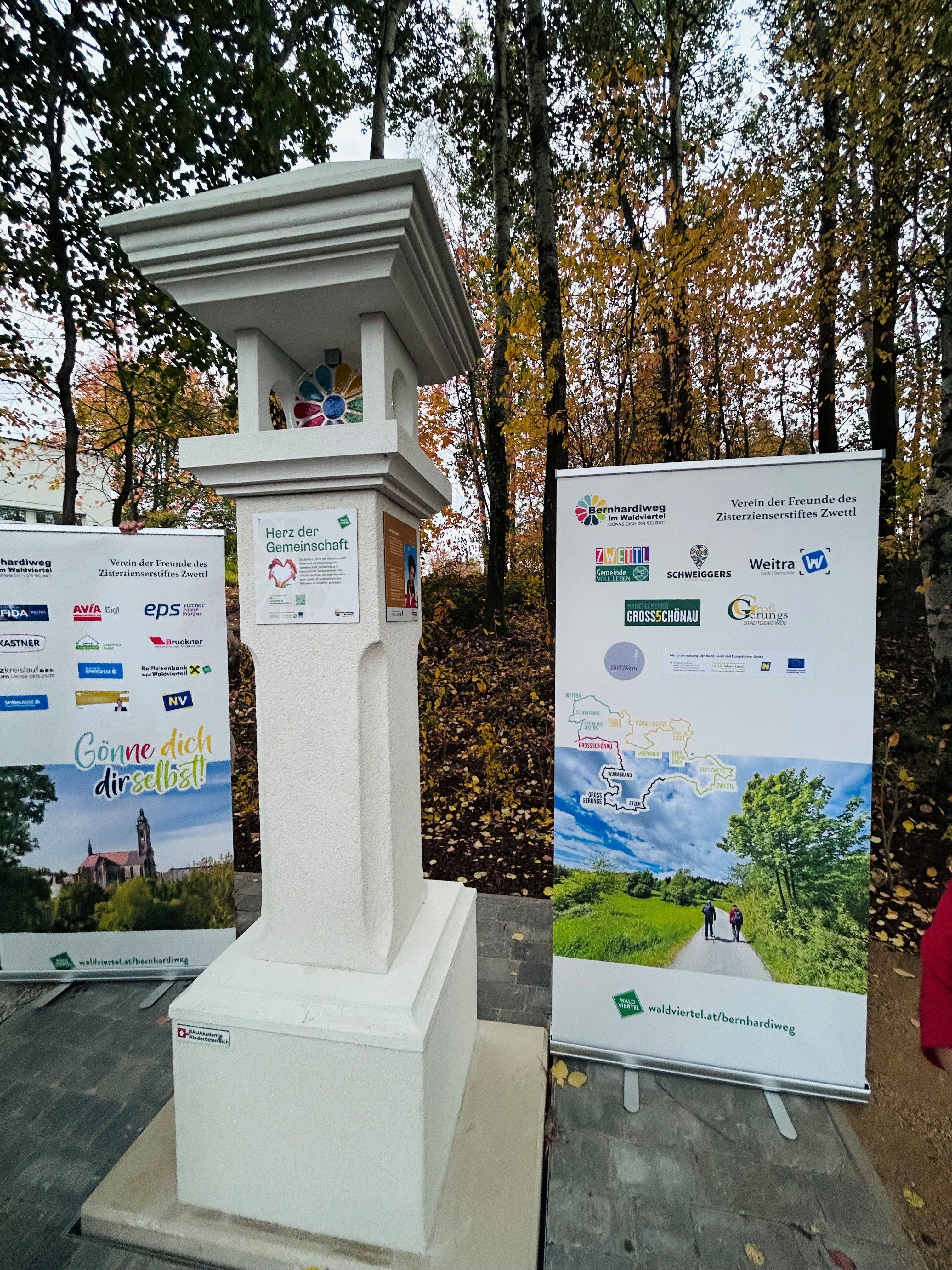 Marterl im Zentrum. Links und Rechts Roll ups.