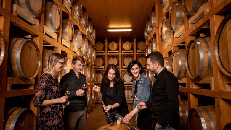 Gruppe von Menschen in einem Lagerraum mit Whiskyfässern.