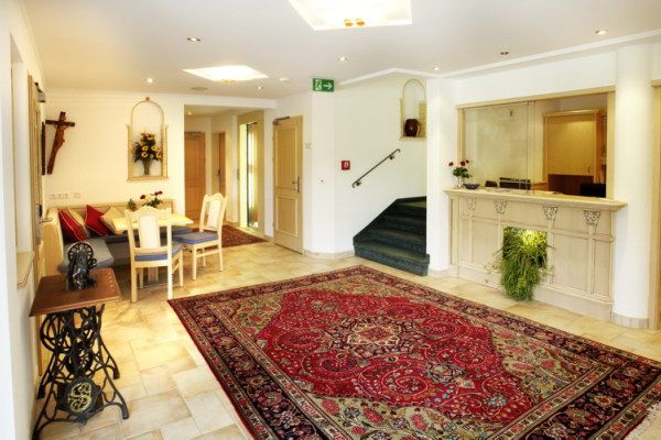 Eleganter Empfangsbereich mit Teppich, Rezeption und Sitzbereich.