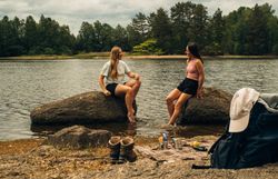 Zwei Frauen, die auf Steinen, im Teich sitzen und sich unterhalten