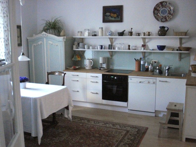 Gemütliche Küche mit Esstisch, Schränken und Regalen.