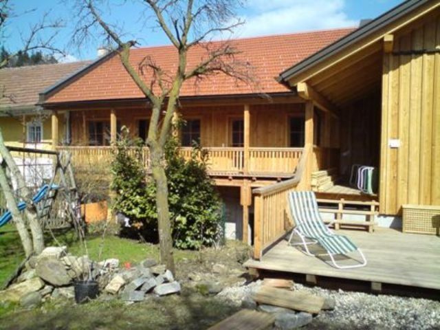 Holzgebäude mit Terrasse und Garten im Vordergrund.