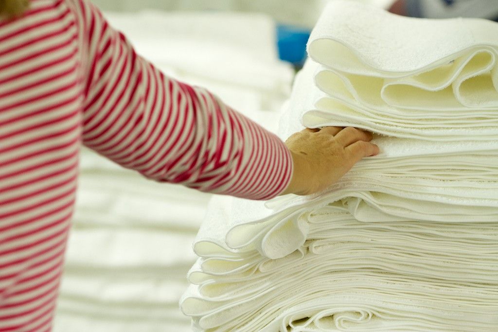 Eine Hand berührt einen Stapel weißer Handtücher.