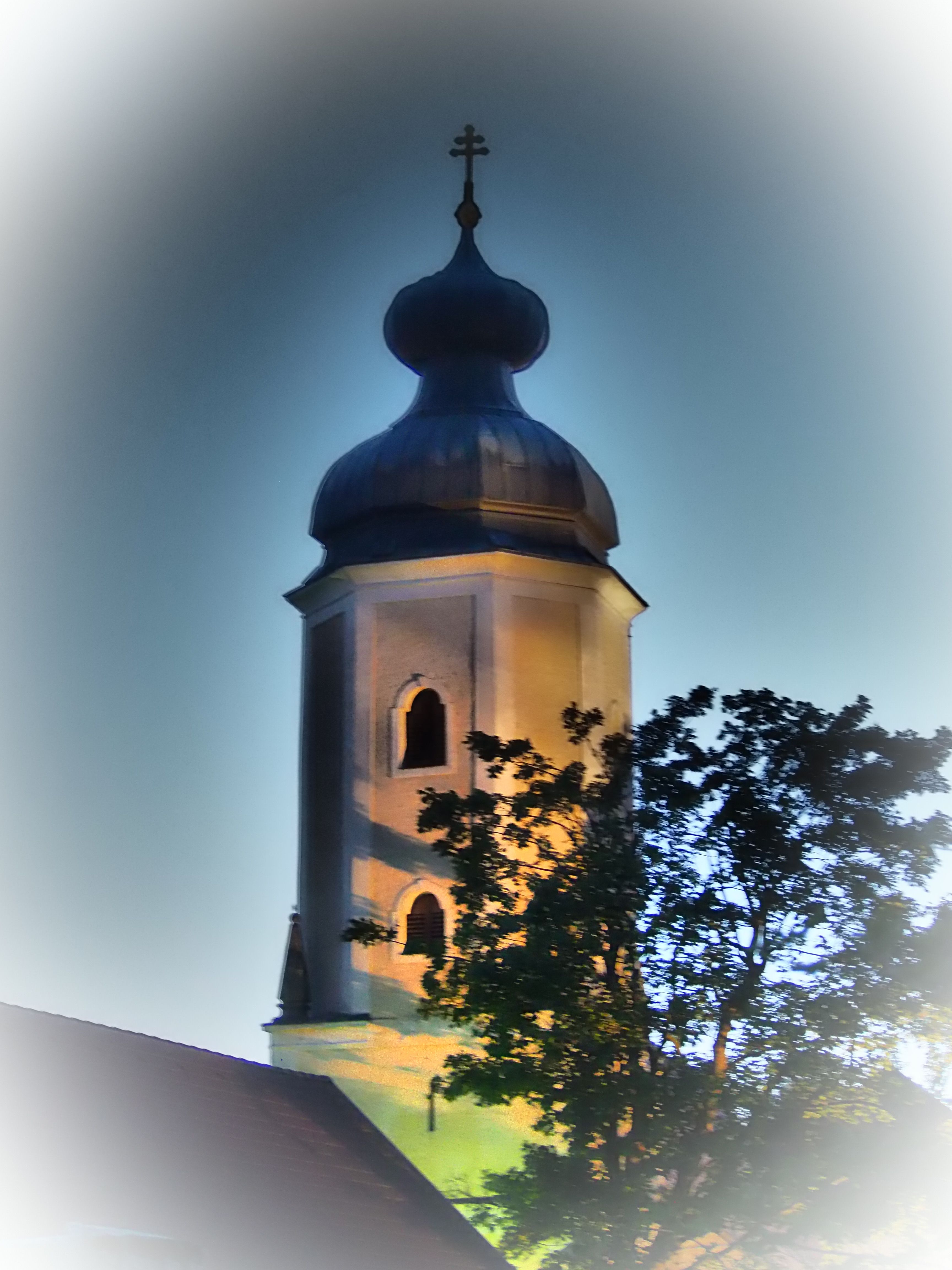Beleuchteter Kirchturm der Pfarrkirche Sallingberg bei Dämmerung.