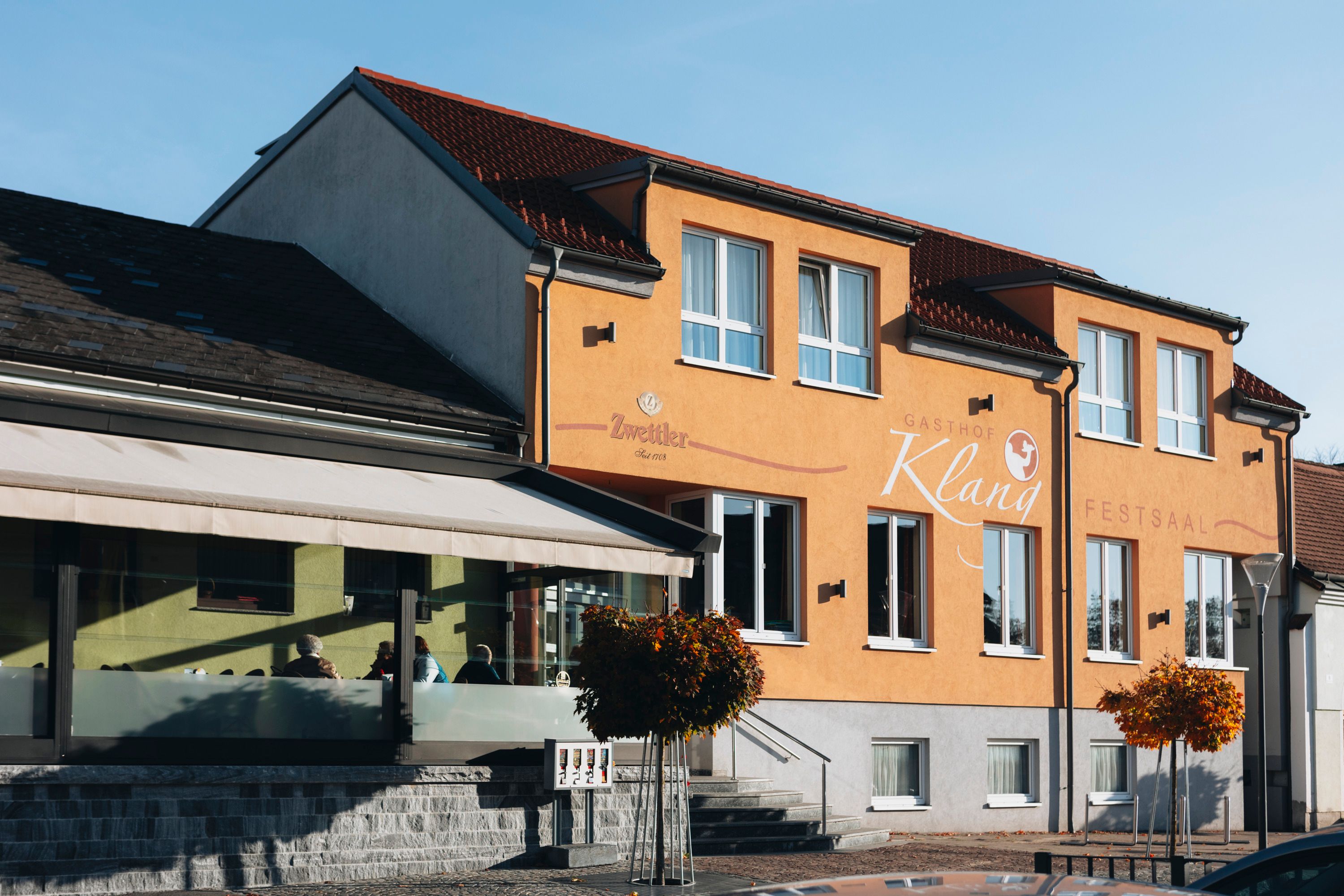 Gasthof Klang in Echsenbach mit gelber Fassade und großen Fenstern.