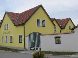Gelbes Gebäude mit rotem Dach und grünen Toren, beschriftet mit 'Gästehaus'.