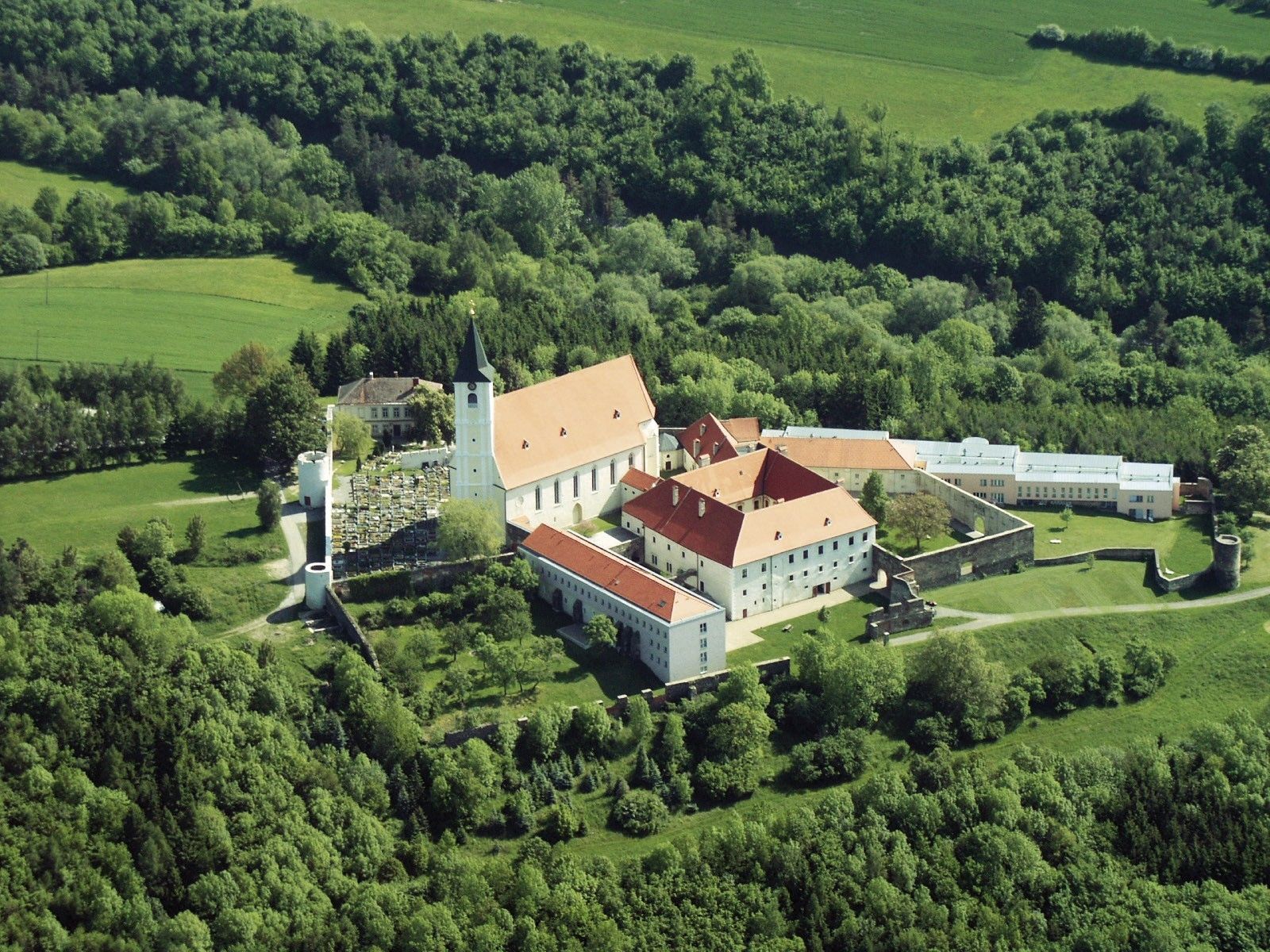 Luftaufnahme eines Klosters inmitten von grüner Landschaft.