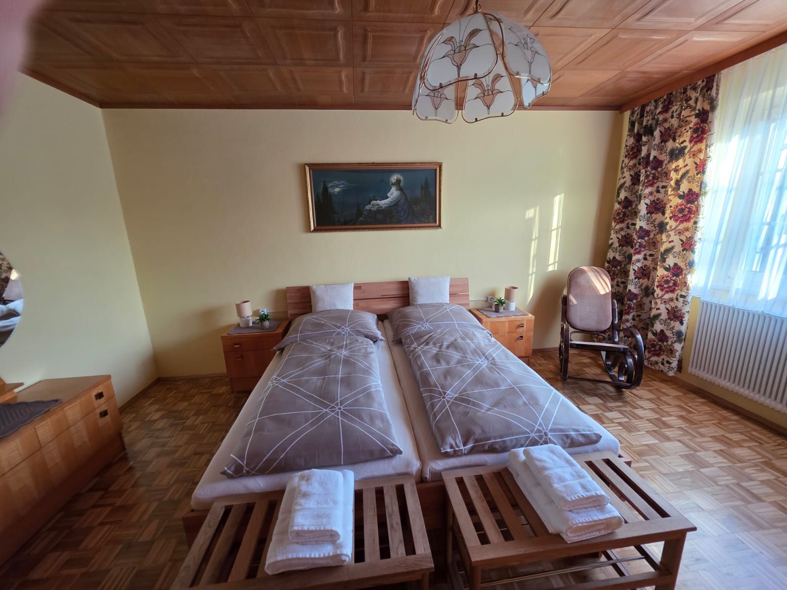 Gemütliches Schlafzimmer mit zwei Einzelbetten, einem Schaukelstuhl und einem Gemälde an der Wand.