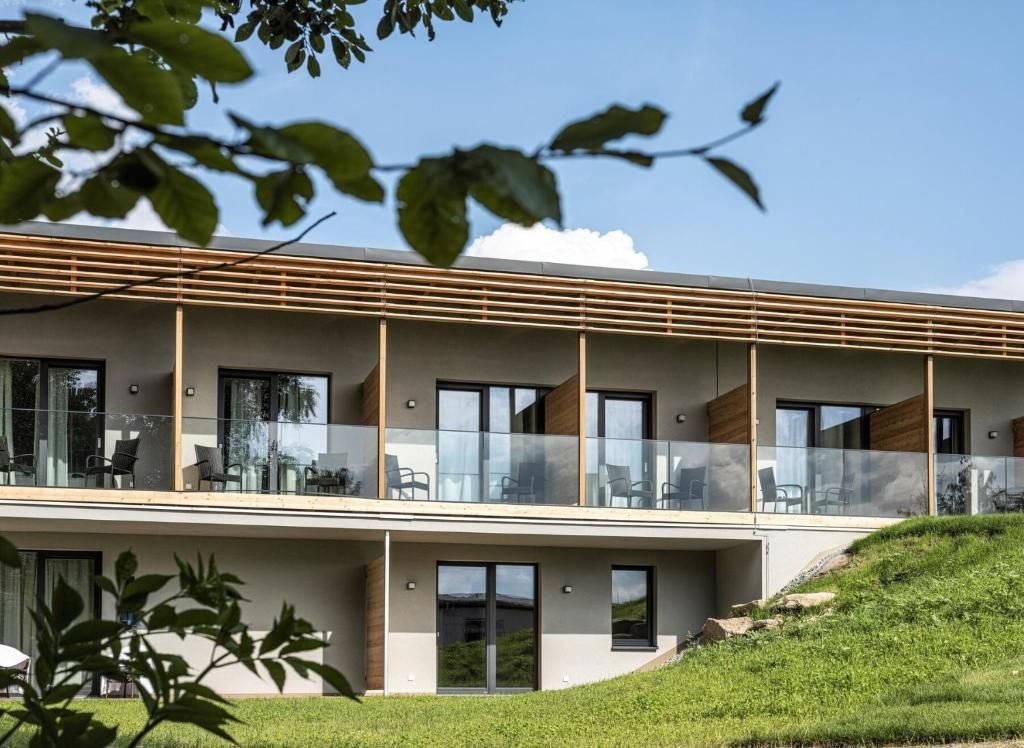 Außenansicht des Hotel Ottenstein – Das Wohlfühlhotel mit moderner Fassade, Balkonen und grünem Hang im Vordergrund.