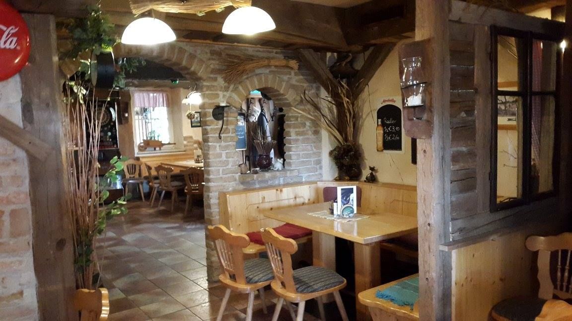 Gemütlicher Innenraum eines rustikalen Pubs mit Holzmöbeln und Backsteinwänden.