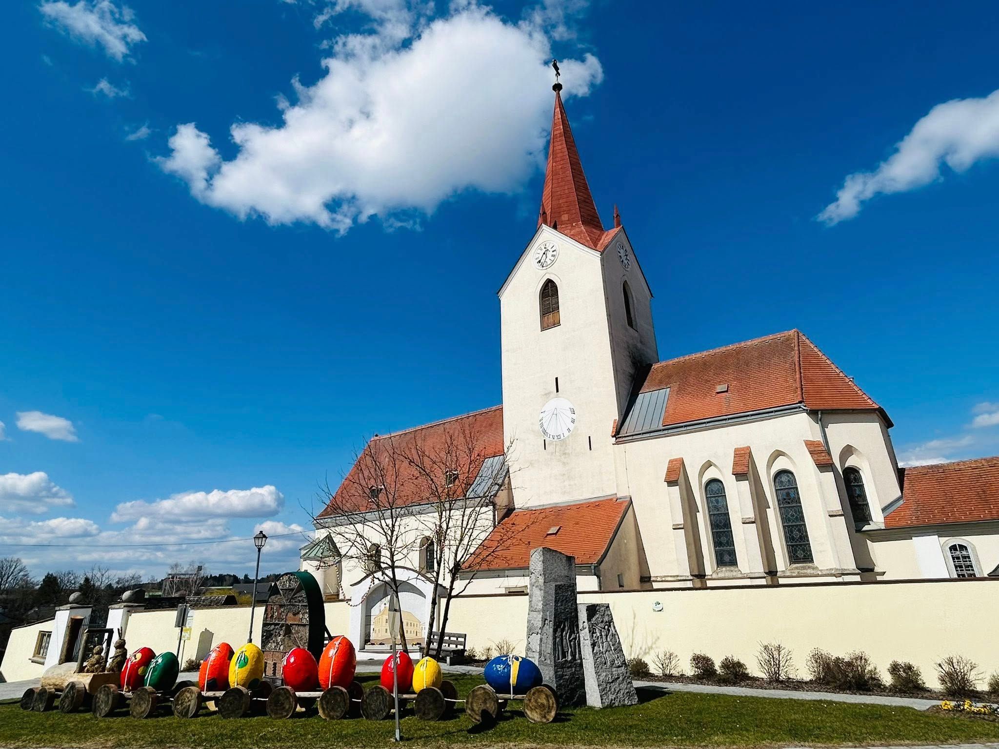 Bunte Ostereier vor einer Kirche. 