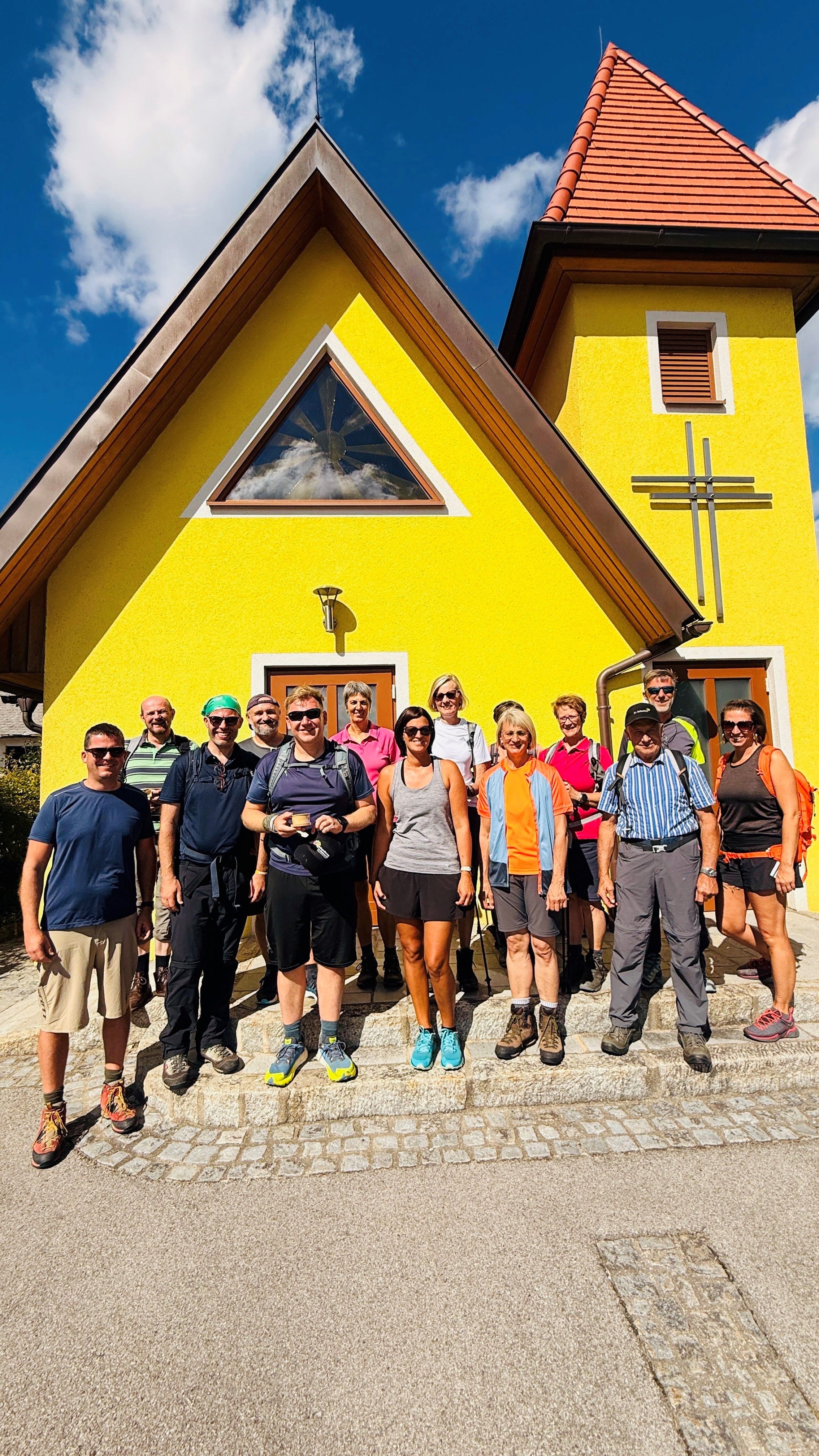 Eine Gruppe von Menschen vor einer gelben Kapelle