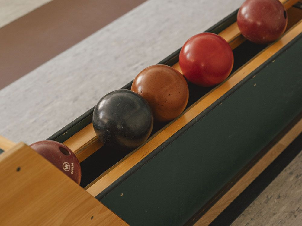 Kegelbahn mit vier Kegelkugeln in einer Halterung.