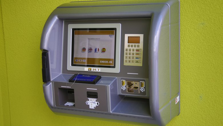 Ein Check-in-Automat an einer grünen Wand.