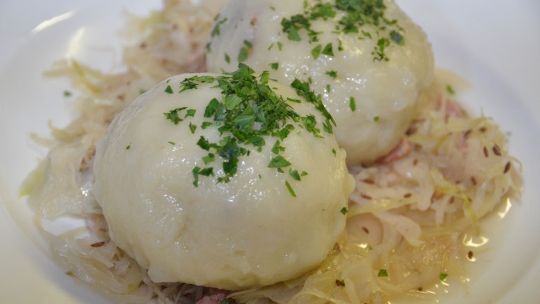 Zwei Grammelknödel auf Sauerkraut, garniert mit Petersilie.