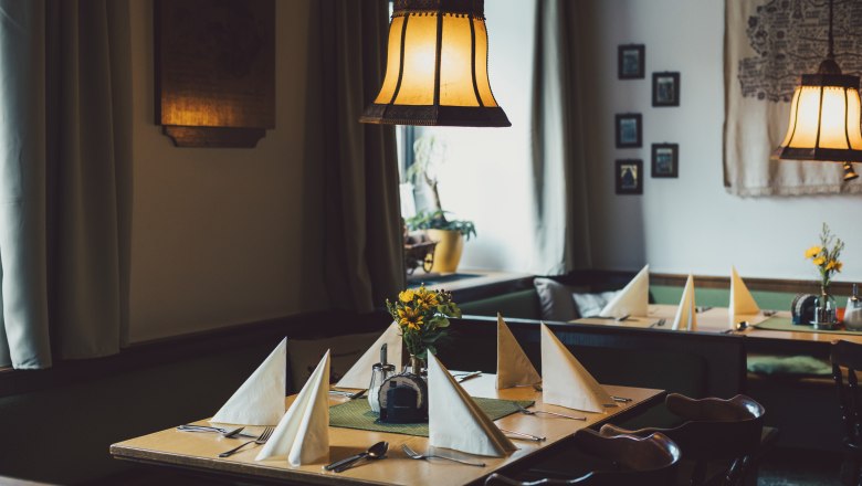 Gemütliche, traditionell eingerichtete Stube mit gedeckten Tischen und warmem Licht.