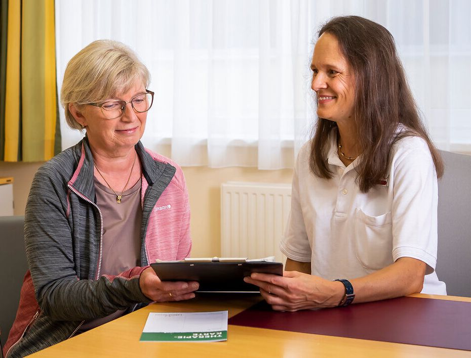 In einem hellen, einladenden Raum findet ein persönliches Arztgespräch statt, das Vertrauen und Fürsorge ausstrahlt. Die entspannte Atmosphäre fördert den Austausch und die individuelle Beratung, während die sanften Farben der Einrichtung eine beruhigende Wirkung haben.