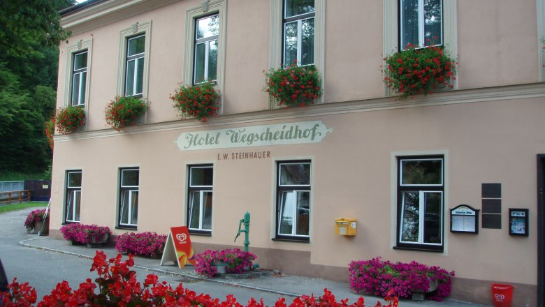 Fassade des Hotels Wegscheidhof mit Blumenkästen und Schildern.