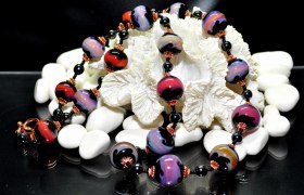 Bunte Perlenkette auf weißen Steinen und Muschel.