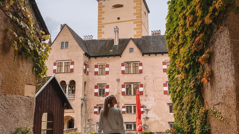 Eine Person geht durch einen mit Efeu bewachsenen Torbogen auf den Innenhof von Schloss Ottenstein zu.