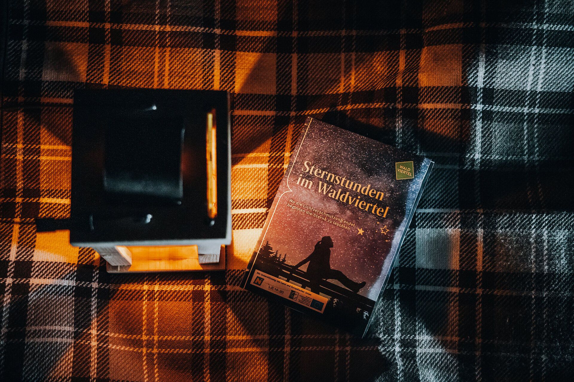 Unter dem funkelnden Sternenhimmel entfaltet sich eine magische Atmosphäre, die zum Träumen einlädt. Die sanfte Beleuchtung einer Laterne wirft warmes Licht auf die Umgebung und schafft einen perfekten Ort für Sternengucker, um die Wunder des Universums zu genießen.