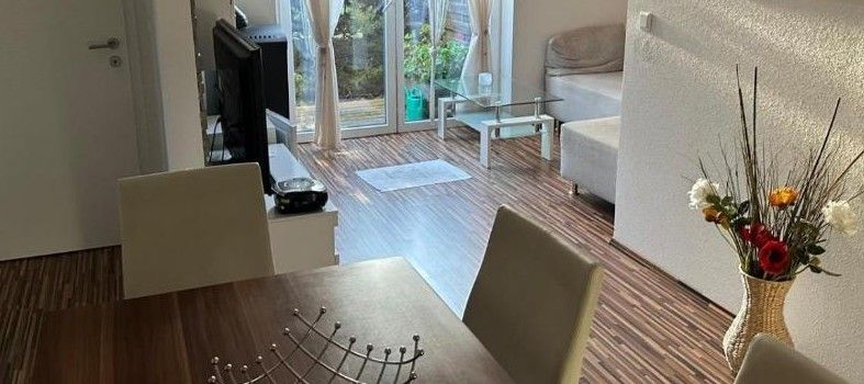 Modernes Wohnzimmer mit Holzboden, Esstisch, Sofa und Glastüren zur Terrasse.