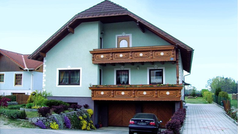Ein zweistöckiges Haus mit Holzbalkon und Garten.