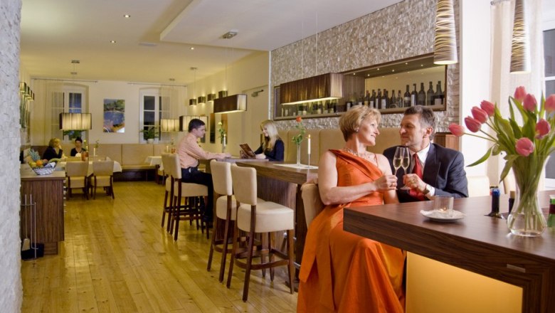 Ein elegantes Restaurant mit Paaren an Tischen und einer Bar.