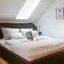 Cozy double room with skylight, modern bed and stylish decorations on the wall.