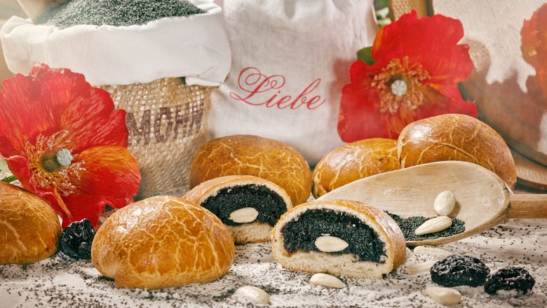 Mohnbrötchen mit Mandeln, Mohnsamen und roten Blumen dekoriert.