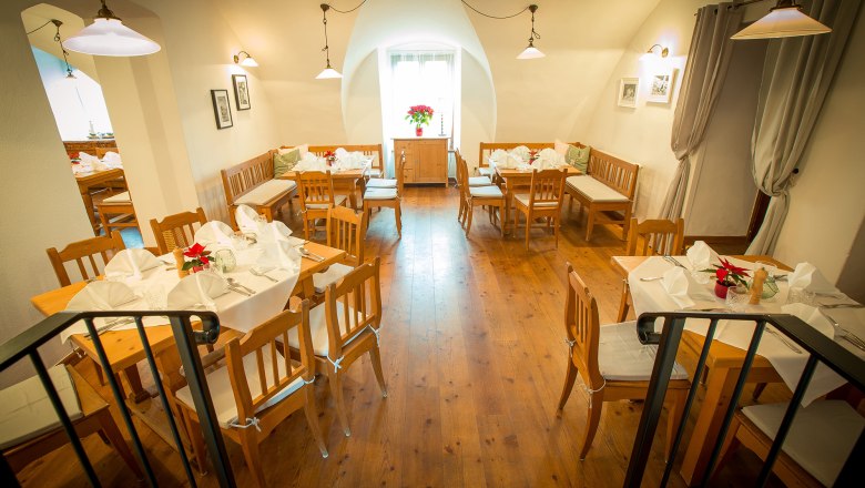 Gemütliches Restaurant mit Holzmöbeln und weiß gedeckten Tischen.