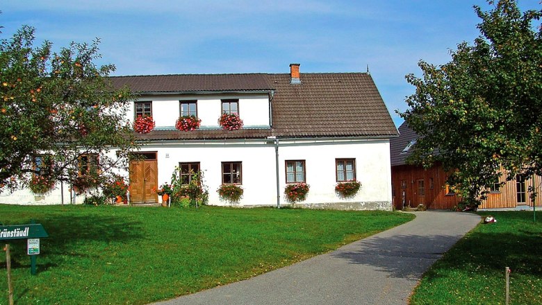 Familie Grünstäudl, © Familie Grünstäudl Ein traditionelles Bauernhaus mit Blumen an den Fenstern und einem gepflegten Garten.