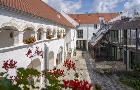 Innenhof mit Arkaden und Glasdach, dekoriert mit Blumen.