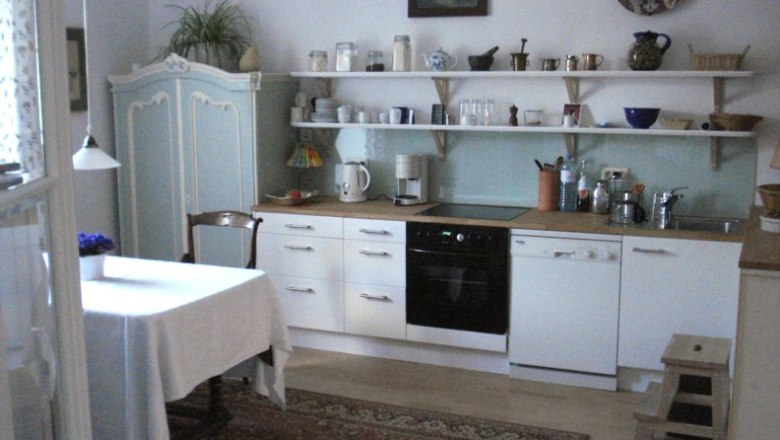Cozy kitchen with dining table, cupboards and shelves.