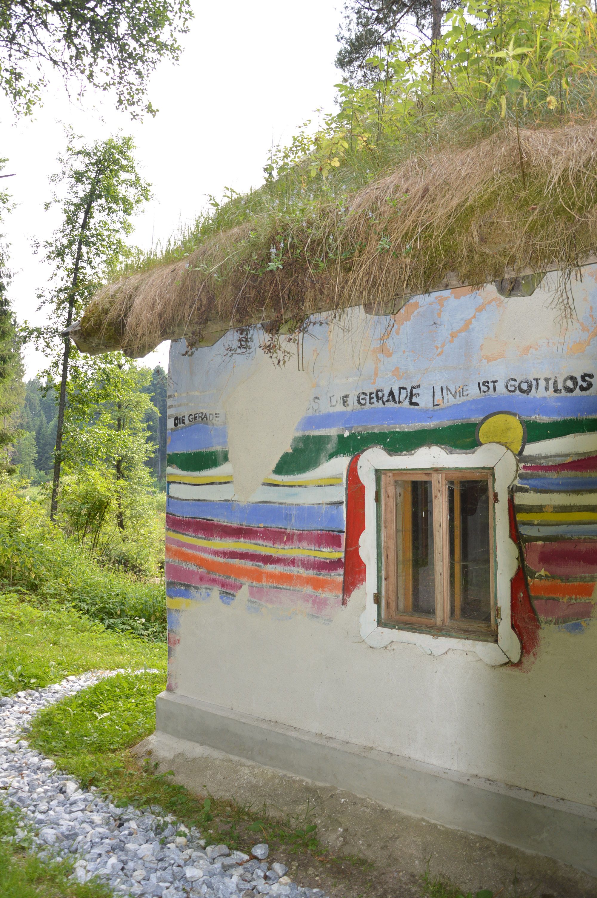 Haus mit bunten Streifen und Strohdach entlang eines Schotterweges