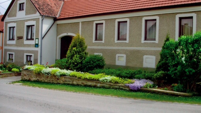 Traditionelles Bauernhaus mit gepflegtem Garten und roten Ziegeldächern.