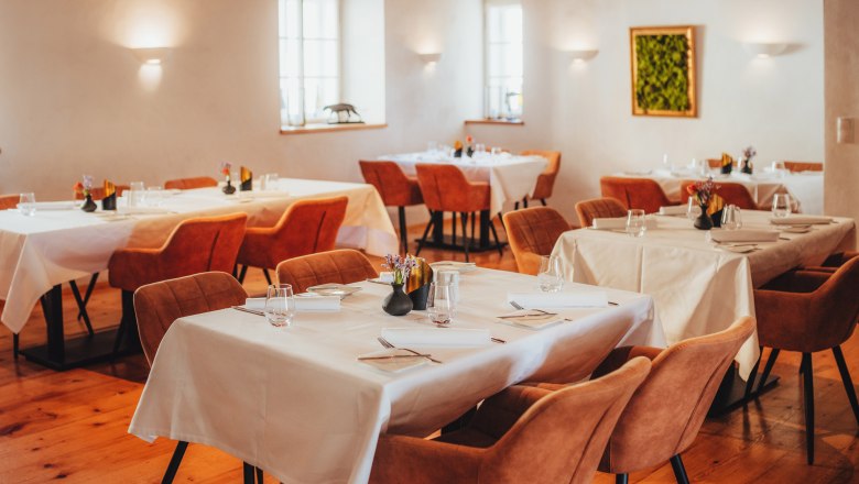 Elegante Gaststube mit gedeckten Tischen und braunen Stühlen.