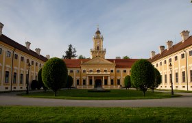 Schloss Jaidhof mit gelber Fassade und Turm, umgeben von gepflegtem Garten.