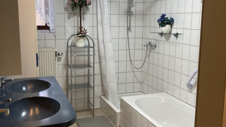 Badezimmer mit Badewanne, Doppelwaschbecken und Dusche mit Duschvorhang.