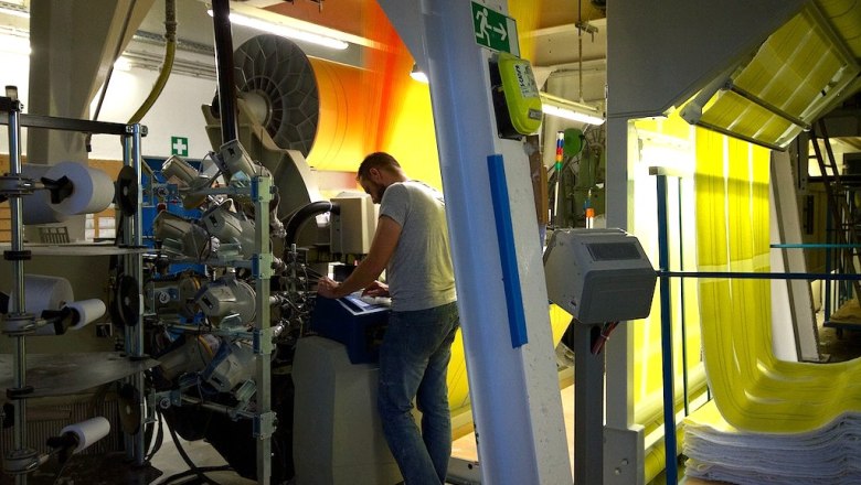 A man works on a machine in a factory with yellow and orange fabric panels.