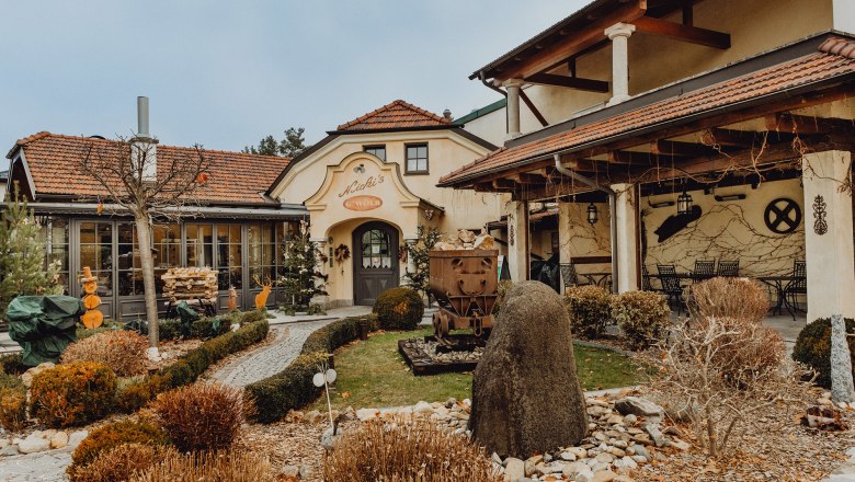 Außenansicht eines traditionellen Wirtshauses mit Garten und Dekorationen.