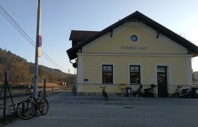Bahnhof Schönberg am Kamp mit Fahrrädern und Rollern davor, umgeben von ländlicher Landschaft.