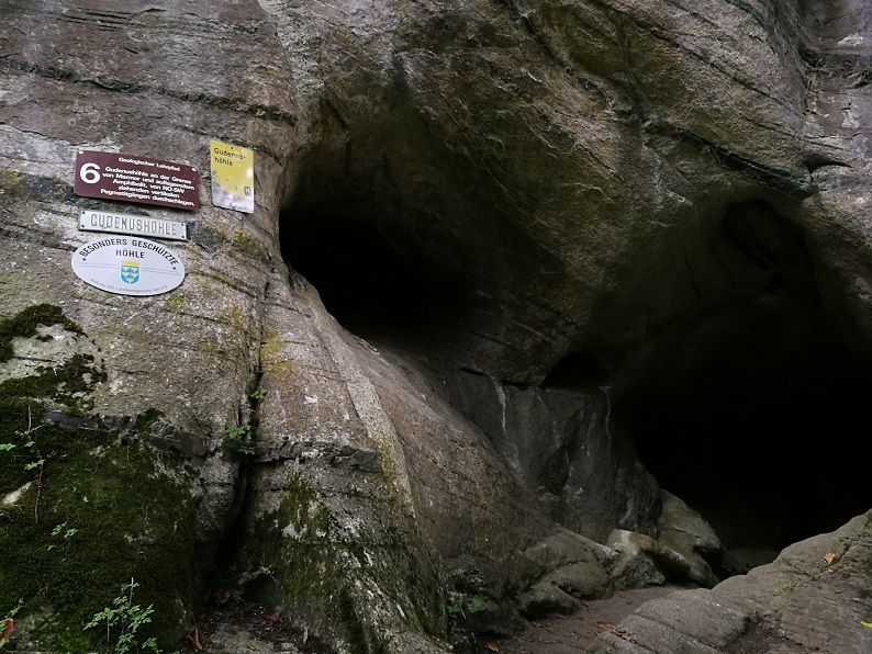 Eingang der Gudenushöhle mit Schildern an der Felswand.