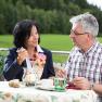 A man and a woman are sitting at an outdoor table enjoying a dessert.