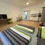 Modern apartment with double bed, TV, dining table and kitchenette.