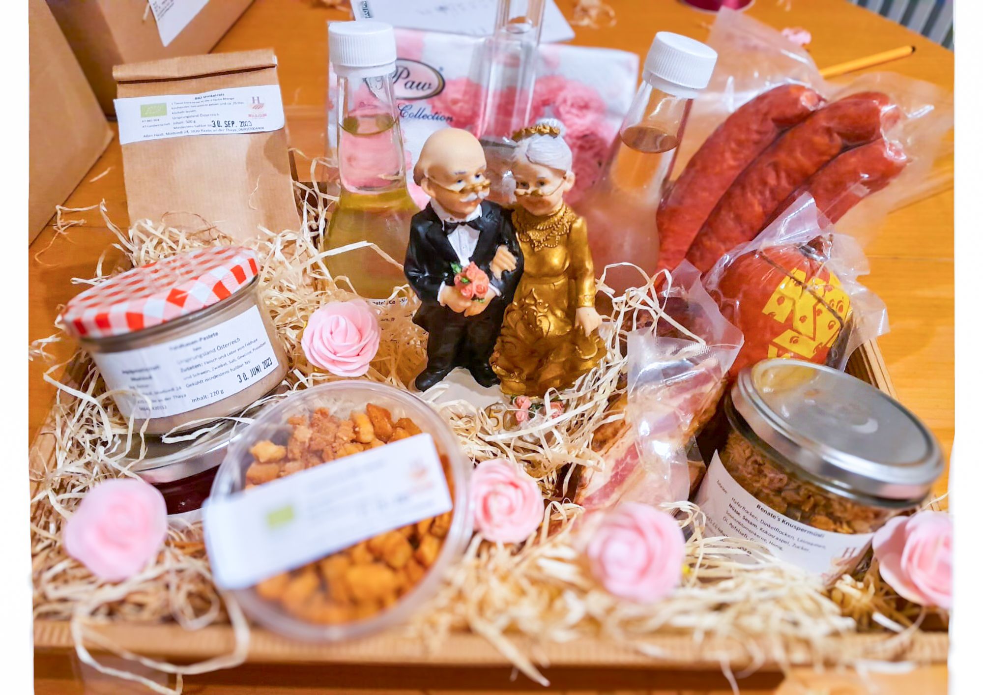 Geschenkbox mit Lebensmitteln und Figuren eines älteren Paares.