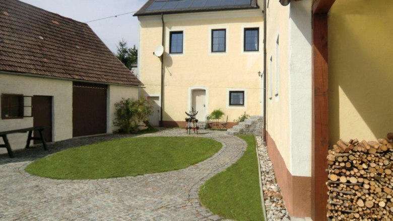 Ein gepflegter Innenhof mit gepflastertem Weg, Rasenfläche und gelben Gebäuden.