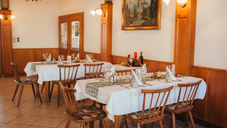 Gemütliches Restaurant mit gedeckten Tischen und rustikaler Einrichtung.